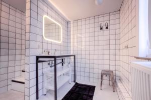 Baño de azulejos blancos con lavabo y espejo en Mons Dragon House en Mons