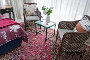 a bedroom with a bed and a table and chairs at Sheilan House in Port Alfred +19 photos