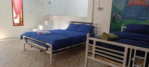 a bedroom with two beds with blue sheets and a mural at Tetebatu Terrace Hostel in Tetebatu