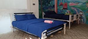 a bedroom with two beds with blue sheets and a mural at Tetebatu Terrace Hostel in Tetebatu