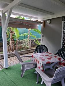 a table and chairs on a porch with a table and a view at Charmant F2 créole in Sainte-Luce