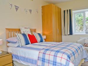 a bedroom with a bed with blue and red pillows at Llwynbedw - 28464 in Cardigan
