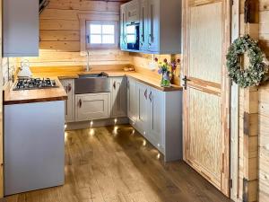 a kitchen with wooden walls and white cabinets at Wind Hall Log Cabin in Gosforth