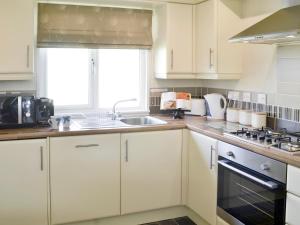 a kitchen with white cabinets and a sink and a window at Willow in Thornbury
