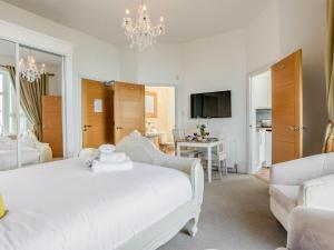 a white bedroom with a bed and a chandelier at The Downs in Torquay