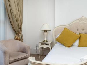 a bedroom with a bed and a chair and a lamp at The Downs in Torquay