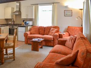 a living room with orange couches and a kitchen at Granary - Ukc3373 in West Down