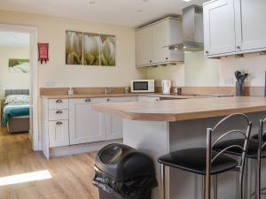 a kitchen with white cabinets and a counter with stools at Sherwood Forest Lodge 1 in Clipstone