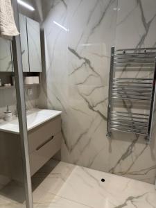 a white bathroom with a shower and a sink at Luxury Apartment 52 Diamond Residences in Skopje +19 photos