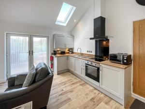 a kitchen with white cabinets and a couch in it at Wyn Shiels Hide Away in Ainstable