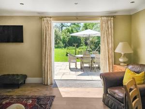 a living room with a couch and a table with an umbrella at Duck Cottage in Winterbourne Dauntsey