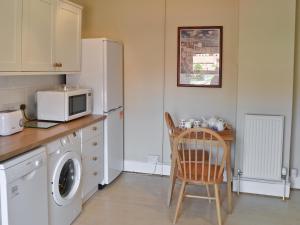 Una cocina con nevera y una mesa con microondas. en Seasands, en Sheringham