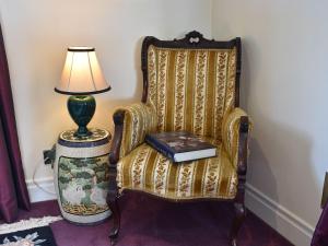 a lamp sitting next to a chair with a book on it at Glebe Farm Cottage in Hornby