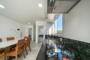 a kitchen with a stove and a table and chairs at Solar do Atlântico 214 in Bombas