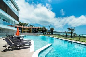 a swimming pool with chairs next to a building at Solar do Atlântico 214 in Bombas