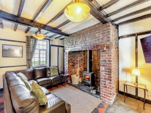 a living room with a couch and a brick fireplace at The Cottage-Uk37339 in Montgomery