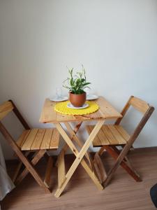 una mesa de madera con 2 sillas y una maceta en ella en Kasadidani Suítes em Lumiar, en Nova Friburgo