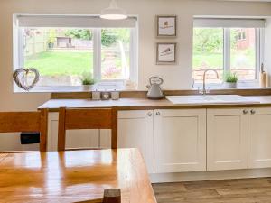 a kitchen with white cabinets and a sink and a window at Southways Cottage in Cumwhinton