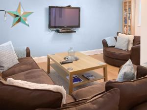 a living room with two couches and a tv at The Old Forge in Alnwick