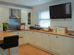 a kitchen with white cabinets and a flat screen tv at The Old Forge in Alnwick