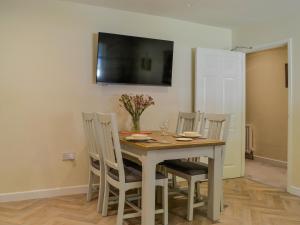 a dining room table with chairs and a television on the wall at Holly - Apartment in Aberfoyle