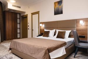 タシュケントにあるArt Dream Hotelの大きなベッドと椅子のあるホテルの部屋