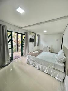 a white bedroom with a bed and a balcony at Quinta Da Bica D'Agua Village in Florianópolis