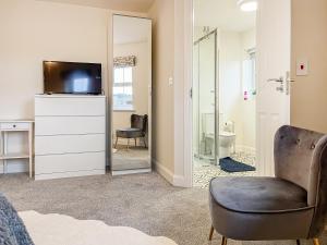 a bedroom with a mirror and a chair at Crawshaw Cottage in Buxton
