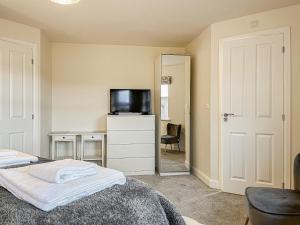 a bedroom with a bed and a desk and a television at Crawshaw Cottage in Buxton