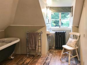 FernhurstにあるOld Rectory Loftのバスルーム(バスタブ、シンク、椅子付) +2枚の写真
