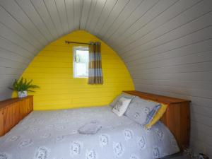 una camera con un letto su una parete gialla di The Hedgehog Pod - Uk50067 a Welshpool