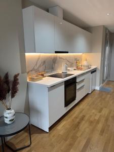 a kitchen with white cabinets and a sink and a table at Luxury Apartment 52 Diamond Residences in Skopje