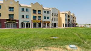 a group of buildings with a grass field in front at Z01 Furnished Studio Garden view International city in Dubai