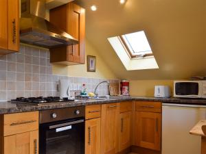 a kitchen with wooden cabinets and a sink and a window at Mange-Tout Maison - Uk32607 in Manton