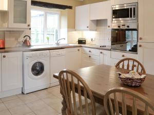 East DownにあるWheelwrightsのキッチン(木製テーブル、椅子、洗濯機付)