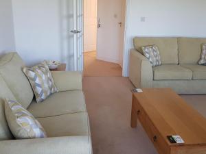 a living room with two couches and a coffee table at Meadowside Apartment in Fowey