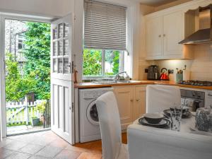 a kitchen with a washing machine and a table with chairs at Cooperative Cottage - Uk44502 in Saddleworth