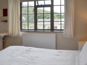 ein Schlafzimmer mit einem weißen Bett und einem Fenster in der Unterkunft Manor Cottage -Ukc3782 in West Down