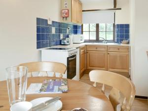 eine Küche mit einem Holztisch mit Stühlen, einem Tisch und einem Tisch in der Unterkunft Manor Cottage -Ukc3782 in West Down