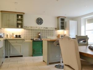 a kitchen with a table and a clock on the wall at Glenmeanich Cottage - Uk33789 in Bridgend