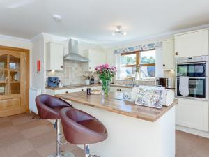 a kitchen with a counter with two chairs and a vase of flowers at The Lookout in Aviemore +32 photos