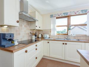 a kitchen with white cabinets and a window at The Lookout in Aviemore