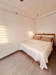 Un dormitorio con una cama grande en una pared blanca. en G's Bnb, en Manila