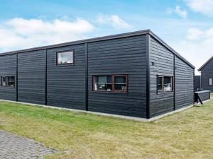 a black house with windows on a grass field at Exclusive Retreat with Spa - By Traum Ferienwohnungen in Rømø Kirkeby