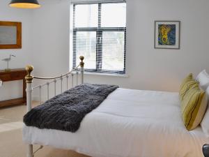 Un dormitorio con una cama blanca y una ventana. en Linhay Apartment, en St Austell