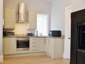 a kitchen with white cabinets and a window at Bag End in Keswick