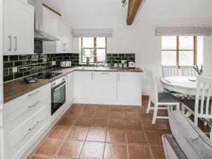 una cucina con mobili bianchi e un tavolo e una sala da pranzo di Uk46555 - Ragleth a Church Stretton