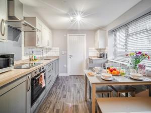 Una cocina con gabinetes blancos y una mesa con frutas encima. en Apartment 1 The Boardwalk - Uk31781, en Great Yarmouth