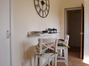 a dining room table with two chairs and a clock on the wall at Roundhill in Eydon
