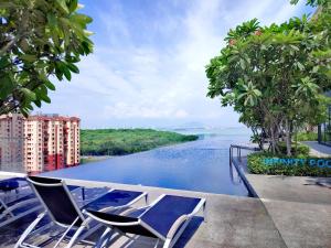 Jelutongにあるurban suites 3 bedroom 10pax a29の水辺の景色を望むプール(椅子付)